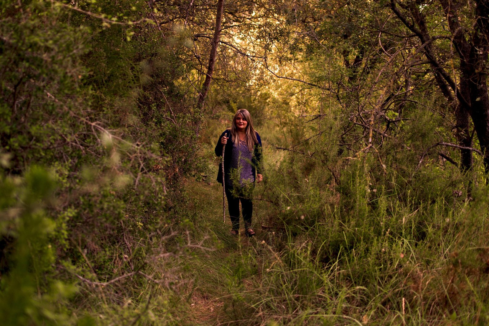 a woman is walking through the woods with a backpack