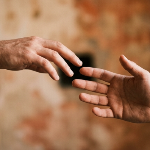 Duas mãos quase se tocando, mas sem se alcançar completamente, como se uma estivesse soltando a outra